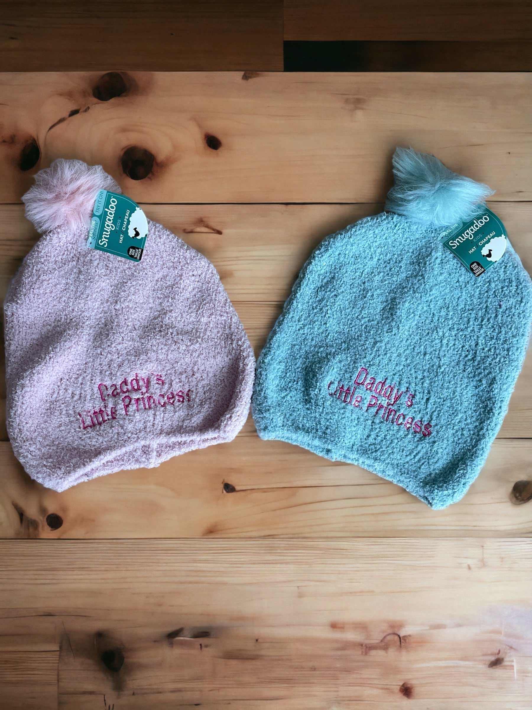 Soft cozy girl hats in pink and teal with "Daddy's Little Princess" embroidery and pom-poms