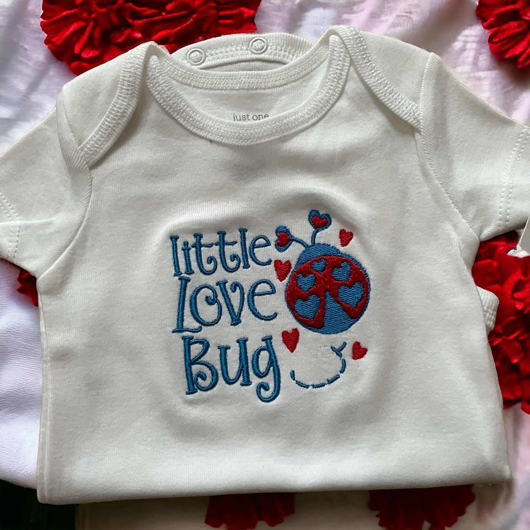 White baby onesie with embroidered blue and red "Little Love Bug" design and hearts, cozy cotton baby clothing, perfect shower gift