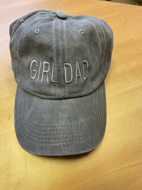 Gray "Girl Dad" baseball hat with adjustable strap resting on wooden surface