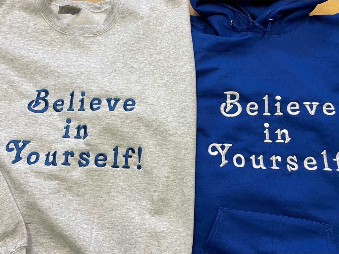 Grey and blue crewneck sweatshirts with "Believe in Yourself" text in cotton fabric