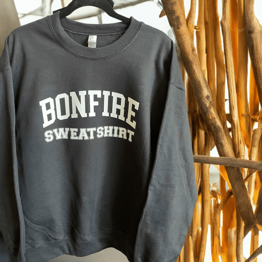 Black Bonfire Crewneck sweatshirt hanging on wooden rack in natural light