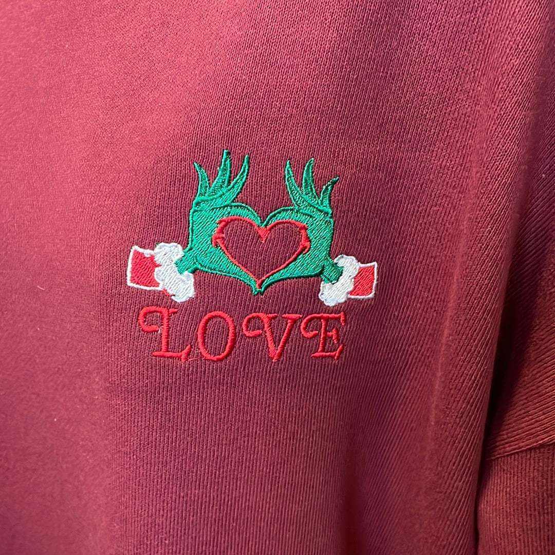 Festive Christmas red sweater with embroidered Grinch hands forming a heart and the word LOVE