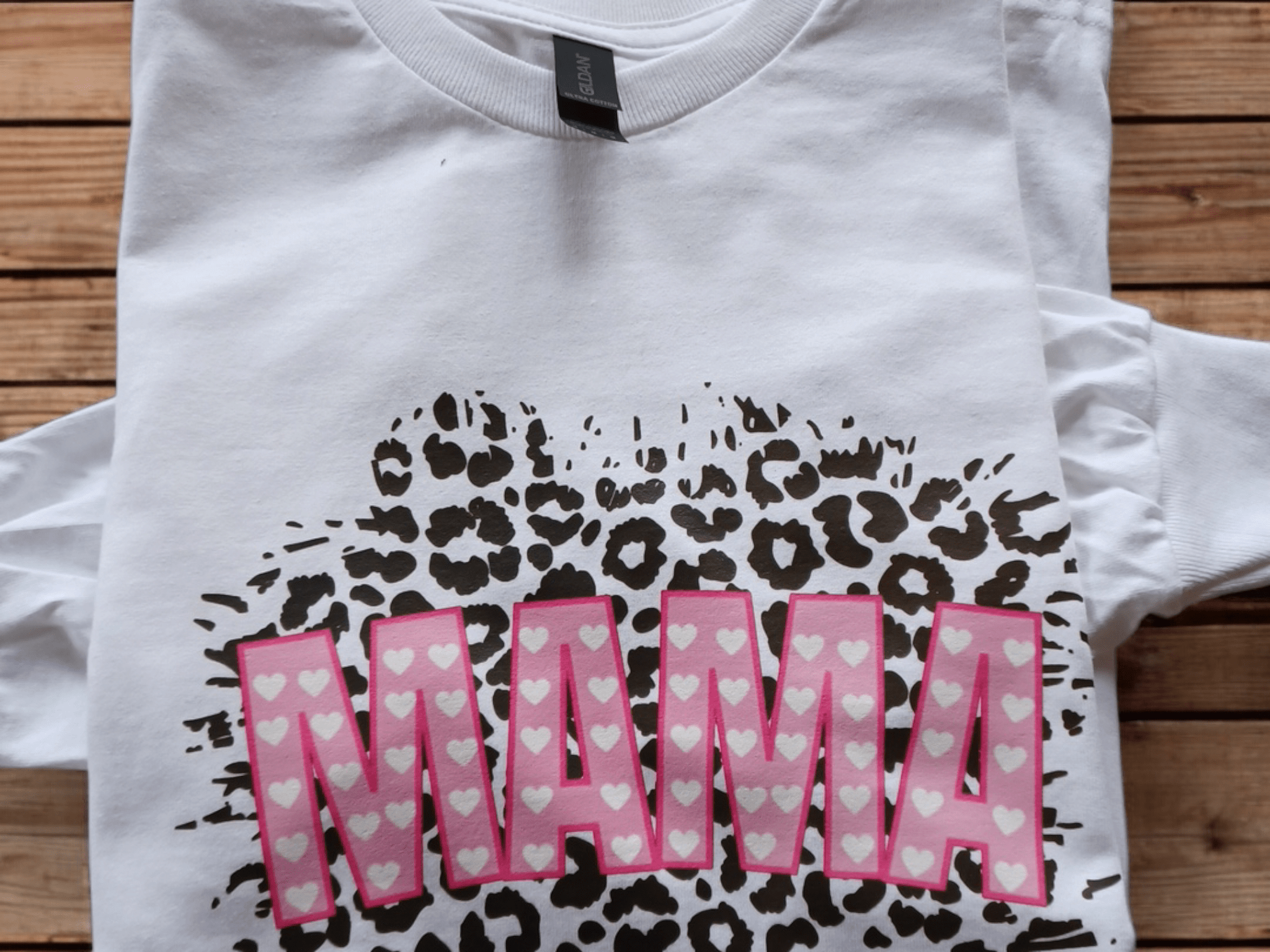 White graphic tee with MAMA text in pink hearts and leopard print background on long sleeve cotton shirt