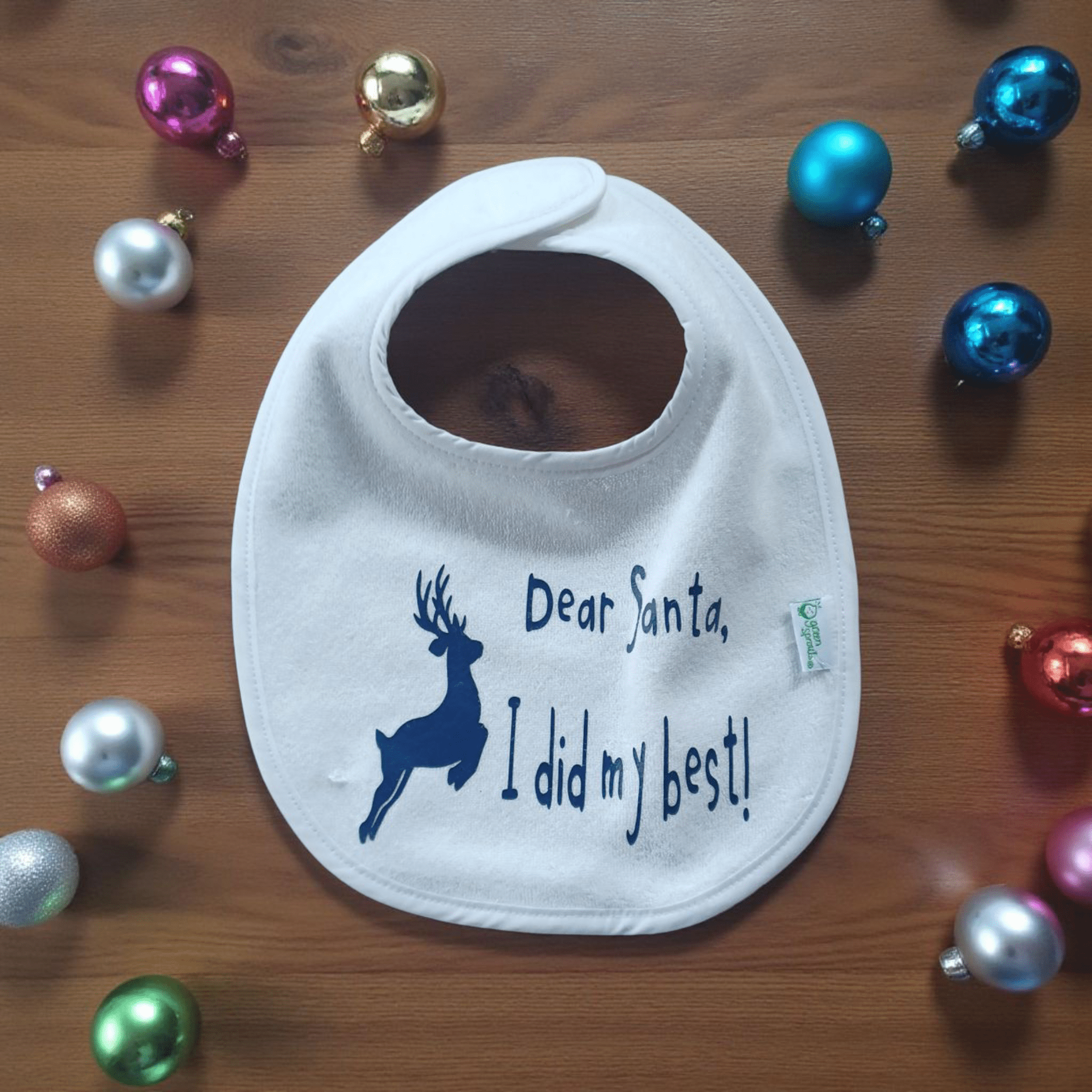 Holiday Baby Bib with "Dear Santa, I did my best!" text and reindeer design surrounded by colorful Christmas ornaments