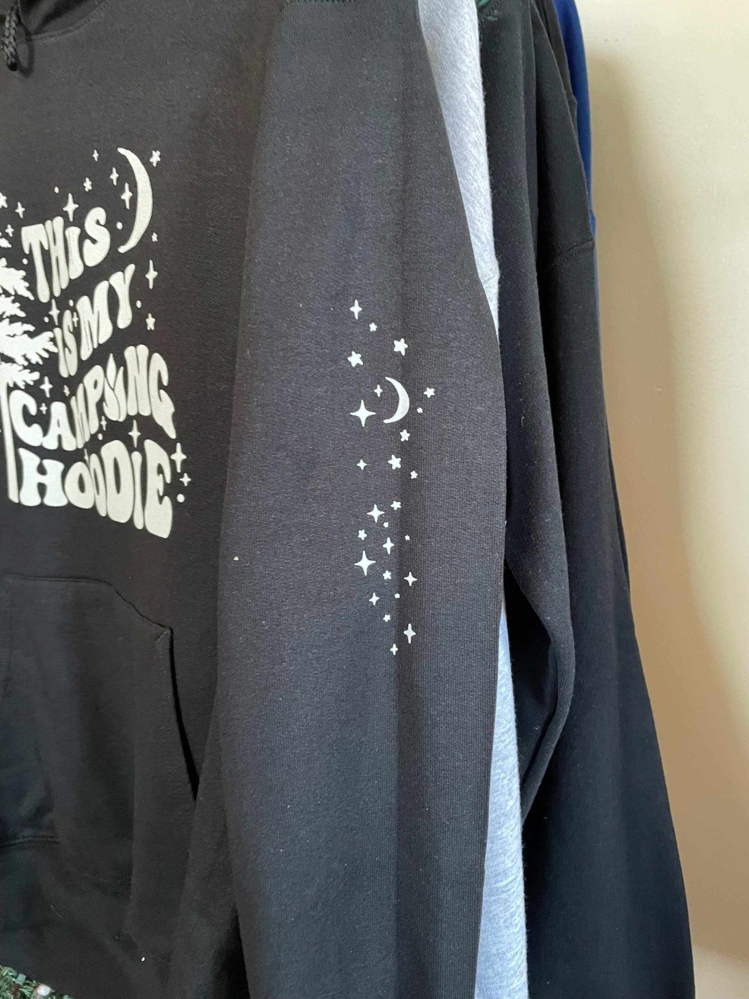Black Gildan cotton blend campfire hoodie with white star and moon design on sleeve and chest text "This is my campfire hoodie"