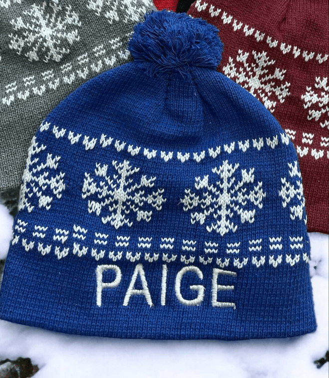 Blue winter beanie with white snowflake pattern and custom embroidered name "PAIGE"
