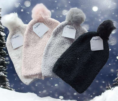 Warm soft acrylic hats with pompom in various colors against a snowy background.