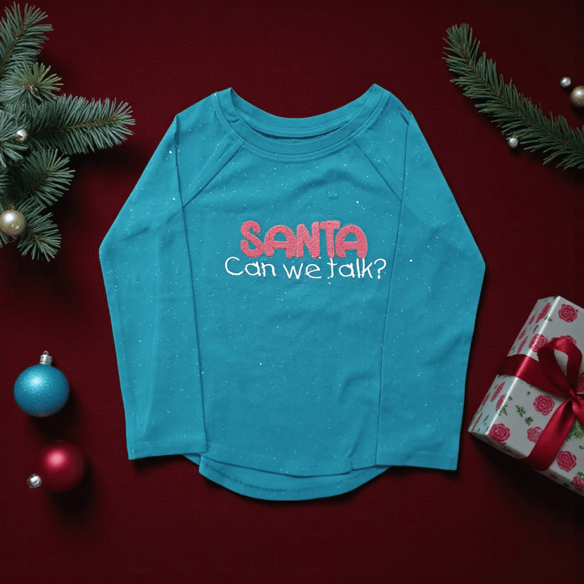 Kids long sleeve blue shirt with Santa Can we talk text and festive Christmas decor background