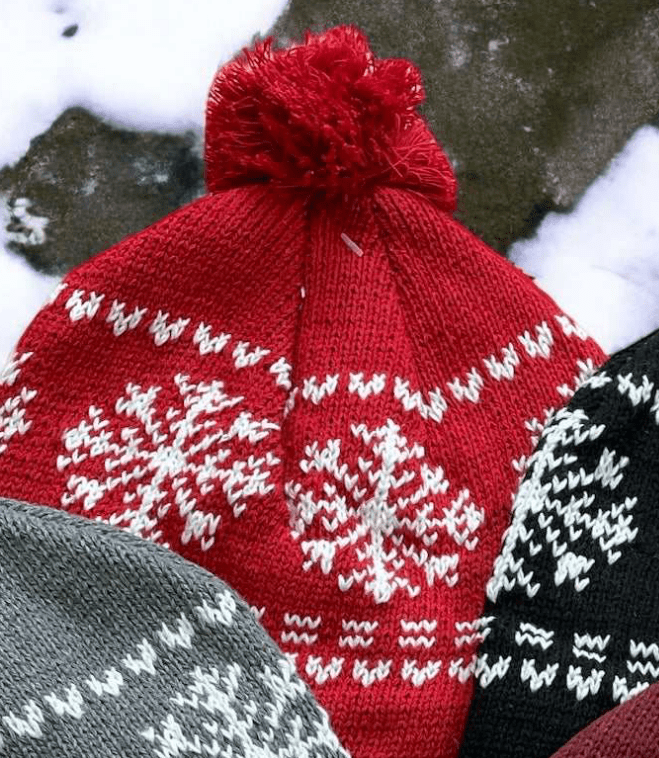 Red snowflake cotton knit hat with tassel, cozy and fleece-lined for winter warmth